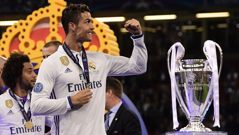 Cristiano Ronaldo wearing the Champions League medal and walking next to the trophy in Cardiff in 2017